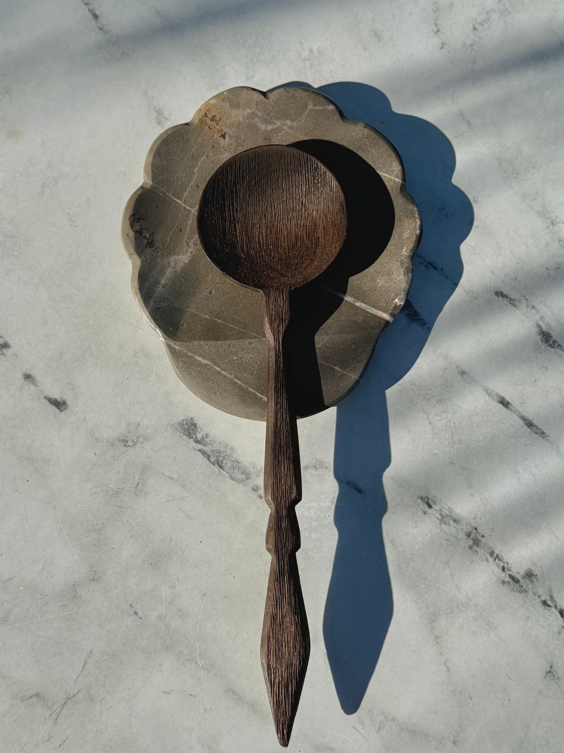 Handcrafted gray marble spoon rest featuring organic stone texture and subtle scalloped edge