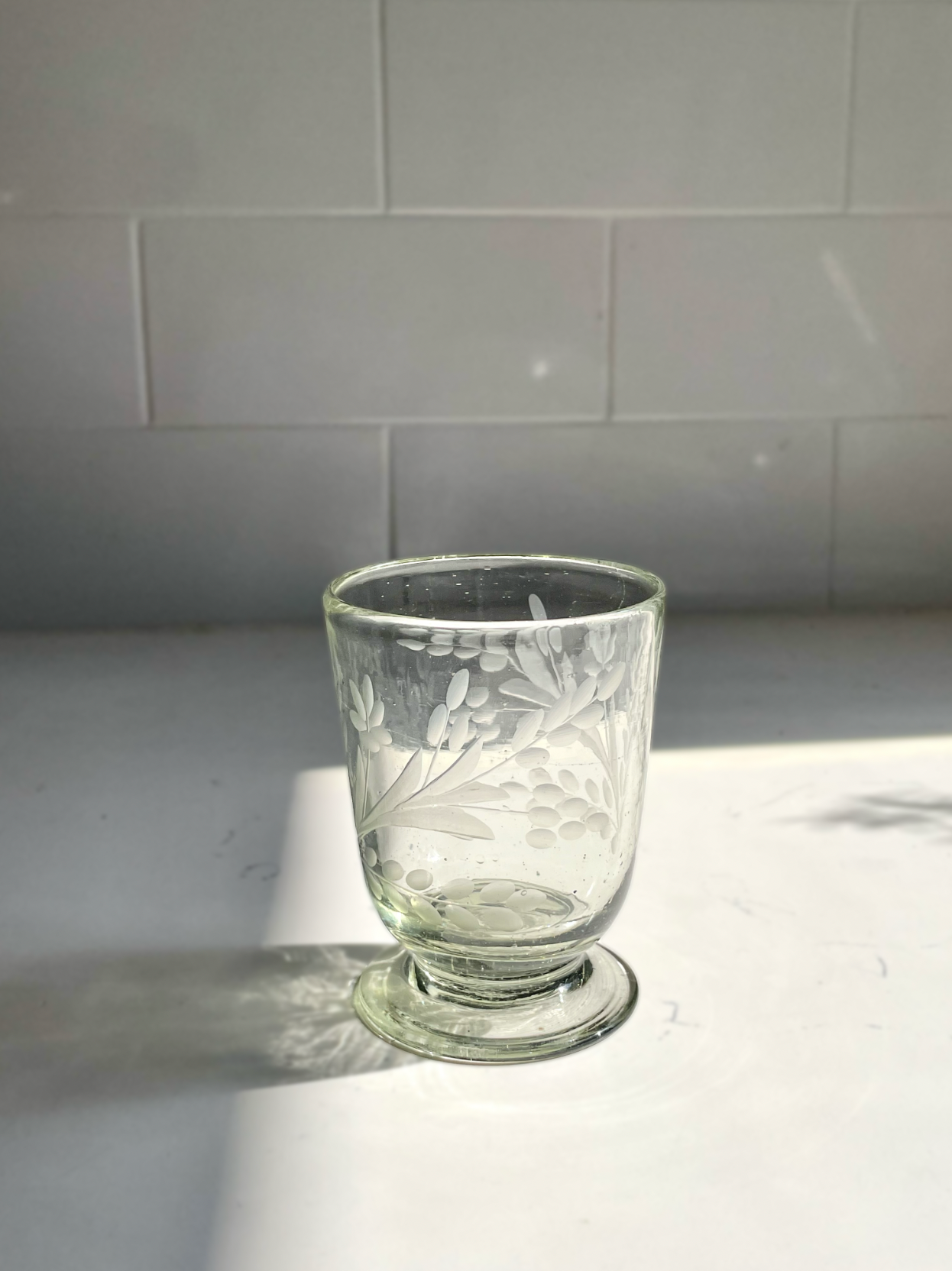 Hand-etched blown footed glass made from recycled glass with floral design, ideal for serving water, wine, or tea
