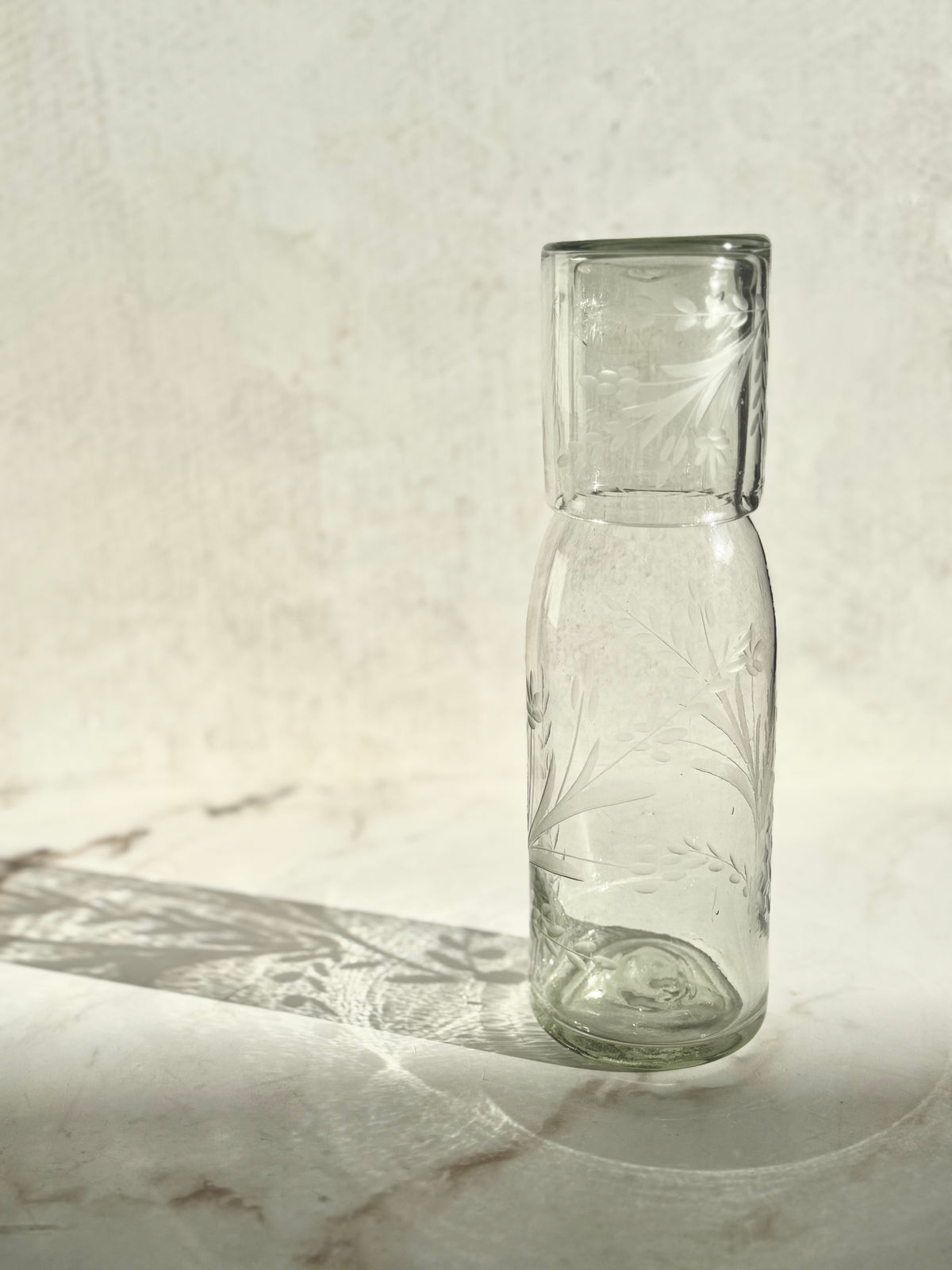 Etched tall carafe and glass set handcrafted from recycled glass with artisanal variations